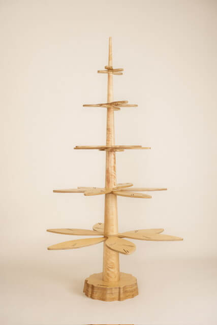 Ein hölzerner Weihnachtsbaum mit vielen runden Gegenständen.